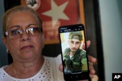 Marilin Vinent sostiene una foto de su hijo Dannys Castillo vestido con uniforme militar. Vinent dijo que su hijo y otros cubanos viajaron a Rusia a finales de julio después de que les prometieran trabajo en una construcción pero terminó en el ejército. (Foto AP/Ramón Espinosa)