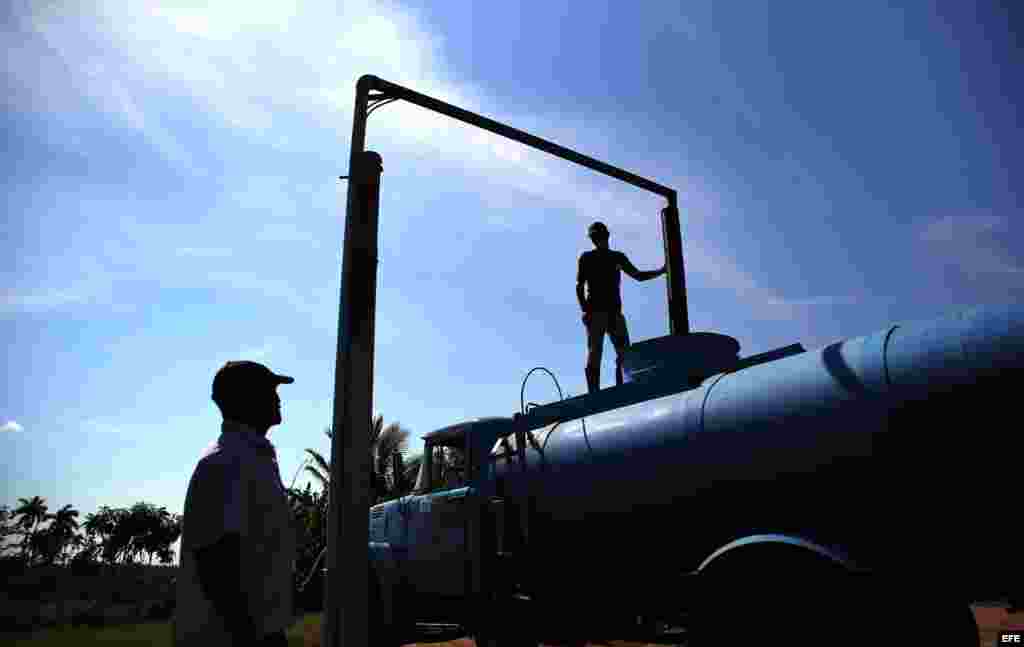 Dos hombres cargan de agua un camión cisterna en la provincia de Ciego de Ávila.