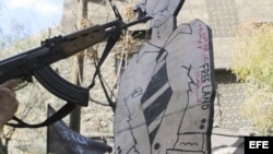 Una persona apunta con un arma a una figura de cartón que representa al presidente sirio, Bachar al-Assad, durante una manifestación contra el régimen sirio. Los rebeldes sirios han tomado el control en las últimas horas de ciudad fronteriza con Jordania