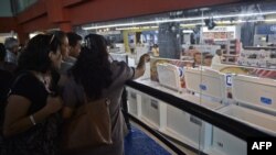 Desde fuera, varias personas contemplan los electrodomésticos a la venta en una de las tiendas que abrieron en octubre en La Habana (Foto de Archivo/Yamil Lage/AFP).
