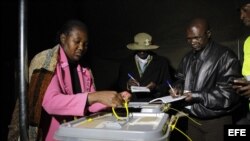 Miembros de la Comisión Electoral de Zimbabue observan mientras se sellan las cajas de votación tras el cierre de los colegios electorales en las elecciones de Zimbaue