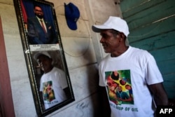 Un residente de la aldea de Arau posa junto a una fotografía del presidente de Guyana, Irfaan Ali. (Roberto Cisneros/AFP)