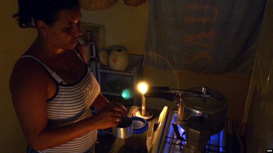Una mujer prepara la comida en la cocina, iluminada con velas, durante un apagón en el barrio de Alamar