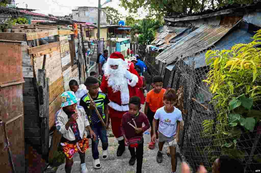 Un hombre vestido como Papá Noel o Santa Claus camina junto a niños cubanos, el 21 de diciembre de 2023. (Foto de Yamil LAGE / AFP)(Foto de Yamil LAGE / AFP)