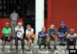 Un grupo de ancianos conversa en la puerta de una bodega.