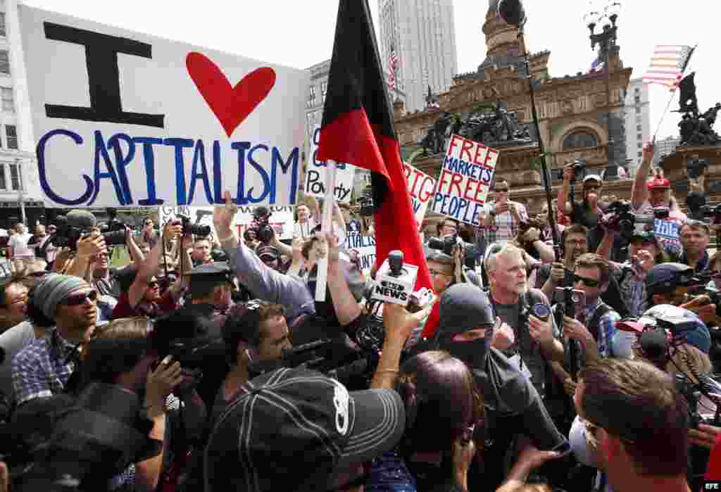 Personas que promueven las virtudes del capitalismo (i) discuten con manifestantes que piden una revolución (d) en un marcha durante el día de cierre.