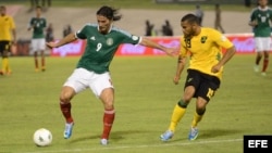 El jugador de México Aldo de Nigris (i) disputa un balón con Adrain Mariappa (d) de Jamaica.