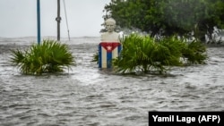 Una estatua de Martí y una bandera cubana en medio de las inundaciones que afectaron este miércoles a la localidad ee Guanímar, en Artemisa, Cuba. ( Yamil Lage/AFP)