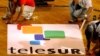  Trabajadores dan los últimos detalles a un cartel publicitario del canal latinoamericano de televisión "Telesur".