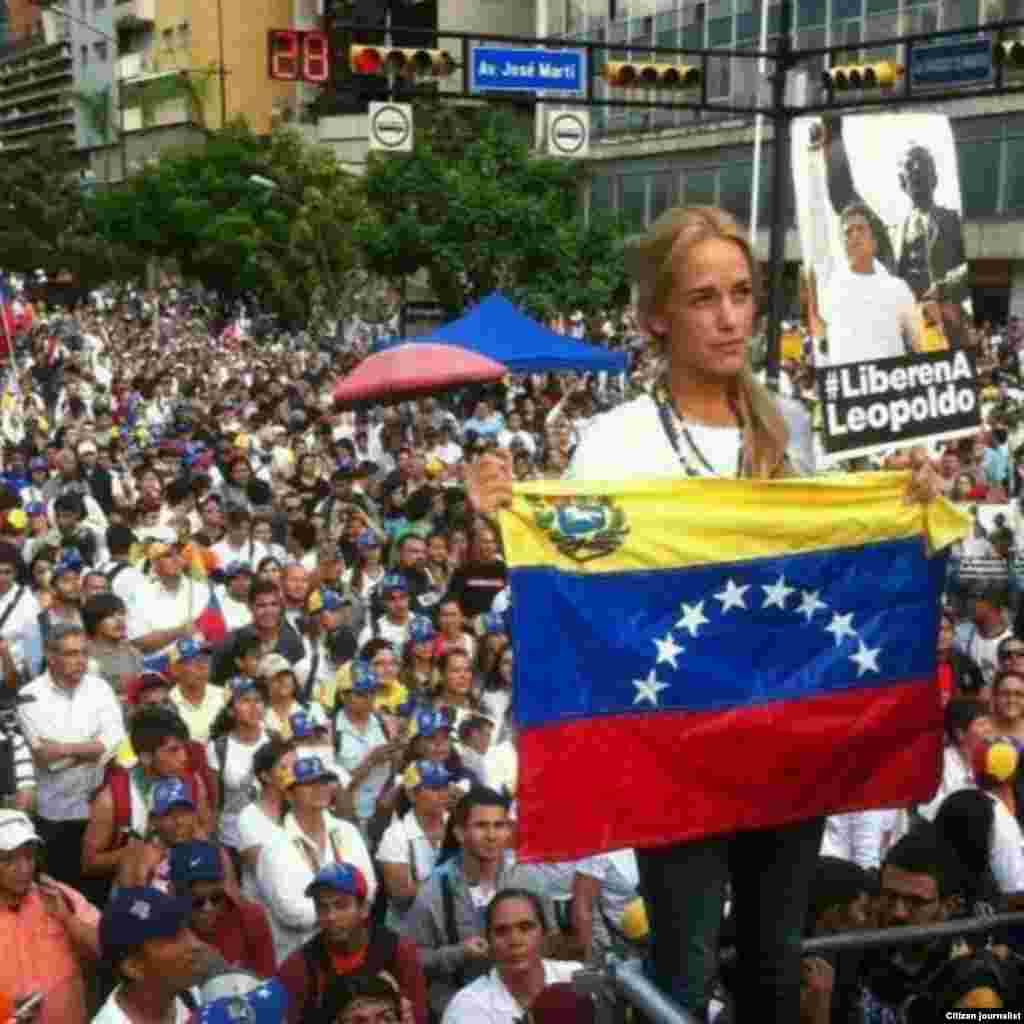La esposa de Leopoldo López sostiene una bandera de Venezuela ante la muchedumbre.