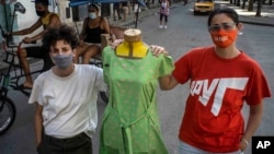 Idania Del Río, izquierda, y Leire Fernández, dueñas de Clandestina, posan con un maniquí vestido con ropa que crearon, afuera de su tienda en La Habana, Cuba, el 18 de febrero de 2021. (AP Foto/Ramón Espinosa)