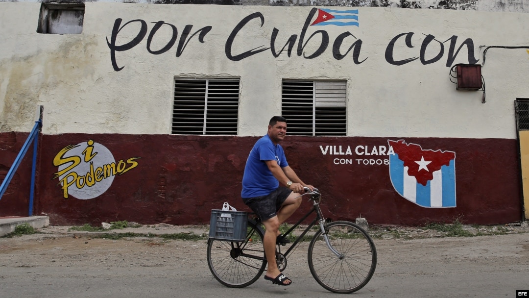 Un hombre cruza en bicicleta frente a un muro con mensajes alusivos a las elecciones generales en Cuba.