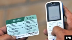 Un hombre recarga un teléfono celular con una tarjeta prepago de la empresa de Telecomunicaciones de Cuba (ETECSA), en La Habana.