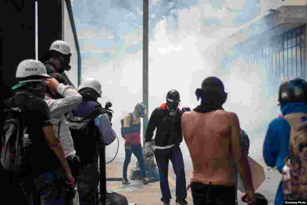 Manifestante encapuchado se aleja de nube de gas lacrimógeno. (Foto: Juan Pablo Arraez)