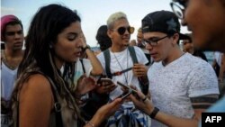 Cubanos verifican conexión a internet en sus móviles durante una prueba de ETECSA.