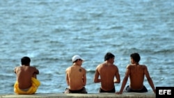 Un grupo de jóvenes conversa en el malecón.