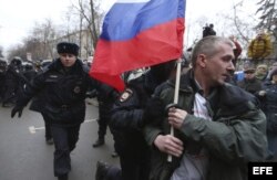Agentes antidisturbios arrestan a un activista con una bandera nacional rusa