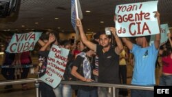 BRA509. RECIFE (BRASIL), 18/02/2013.- Manifestantes que rechazan la visita al país de la disidente cubana Yoani Sánchez, sostienen carteles hoy, lunes 18 de febrero de 2013, en el aeropuerto internacional Guararapes, de la ciudad de Recife (nordeste de Br