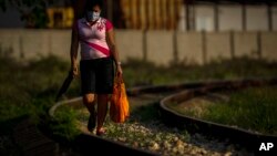 Una mujer camina con provisiones a lo largo de la línea del ferrocarril en una zona rural de La Habana. (AP/Ramón Espinosa)