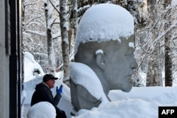 Un hombre fuma cerca de la estatua de Lenin en un parque de Razliv, a las afueras de San Petersburgo, este 21 de enero de 2024. (Olga MALTSEVA/AFP)