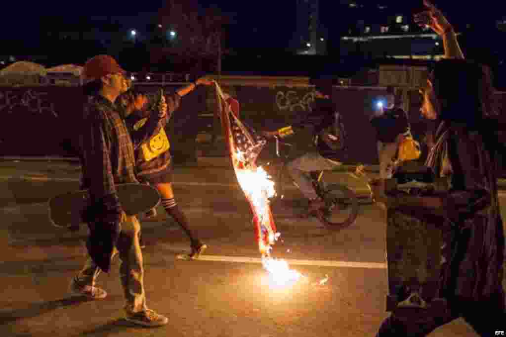 Un manifestante lleva una bandera estadounidense en llamas durante una protesta en Oakland, California (EEUU) contra la elección del republicano Donald Trump como nuevo presidente estadounidense. &nbsp;