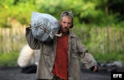 Un campesino cubano carga un saco de carbón.