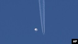 En esta foto proporcionada por Brian Branch, un gran globo se desplaza por encima de la zona de Kingstown, Carolina del Norte, mientras por debajo se observa un avión y la estela que deja a su paso. (Brian Branch vía AP)