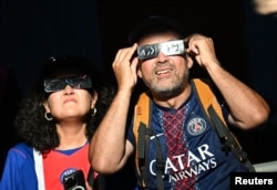 Aficionados del Paris Saint-Germain observan el eclipse solar con gafas protectoras en Salzburgo, Austria - 12 de agosto de 2026. REUTERS/Angelika Warmuth