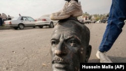 Un combatiente opositor pisa la cabeza de un busto roto del fallecido presidente sirio Hafez Assad en Damasco, Siria, el 8 de diciembre de 2024. (AP Foto/Hussein Malla)