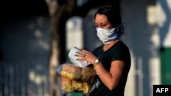 Una mujer con máscara protectora lleva el pan a casa, en La Habana. (Yamil Lage/AFP).