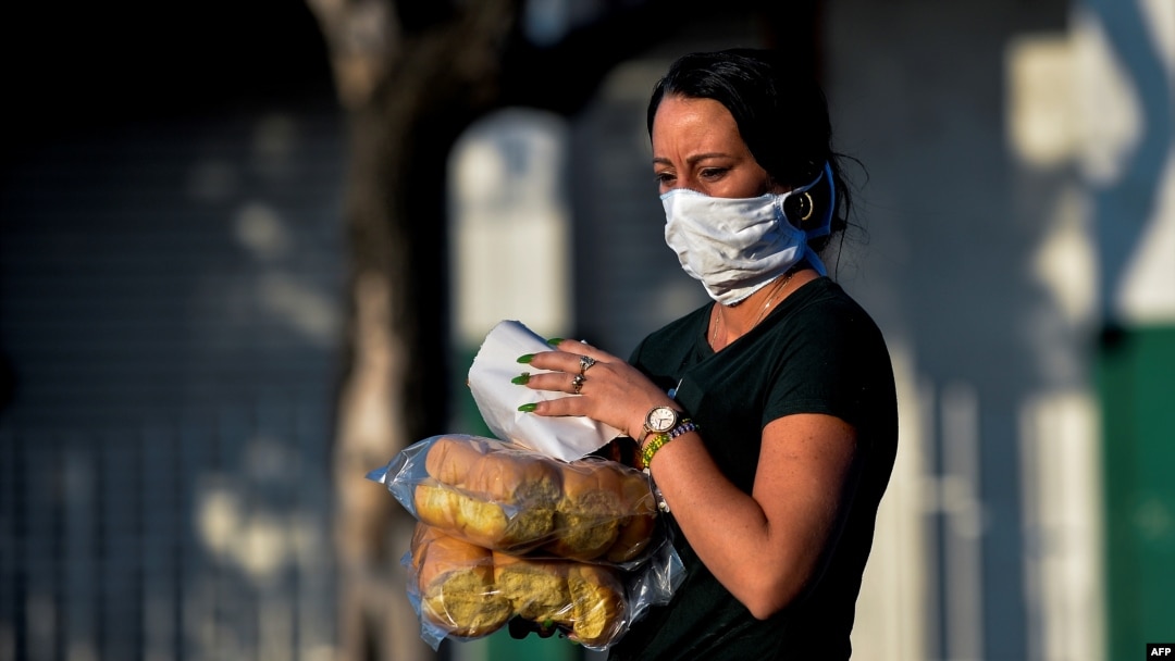 Una mujer con máscara protectora lleva el pan a casa, en La Habana. (Yamil Lage/AFP).