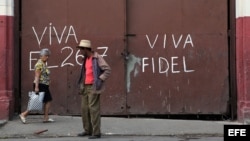 Unas personas caminan frente a un mensaje alusivo al líder cubano Fidel Castro, en un barrio de La Habana (Cuba).