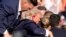 El candidato presidencial republicano, el expresidente Donald Trump, recibe ayuda para bajar del escenario en un evento de campaña en Butler, Pensilvania, el sábado 13 de julio de 2024. (Foto AP/Gene J. Puskar)