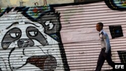 Un policía camina junto a un grafiti en una calle de La Habana (Cuba), hoy, domingo 26 de enero de 2014, dos días antes del inicio de la II Cumbre de la Comunidad de Estados Latinoamericanos y del Caribe (Celac). Calles cerradas, desvíos del transporte pú