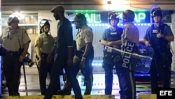Policías y manifestantes en Ferguson, Misuri, tras el toque de queda. 
