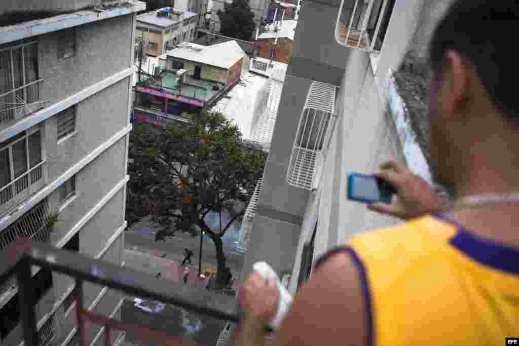 Un joven graba desde la azotea de un edificio en la Plaza Altamira de Caracas (Venezuela). Los vecinos de la céntrica plaza de Chacao viven a diario las consecuencias de los enfrentamientos entre opositores y las fuerzas del orden.