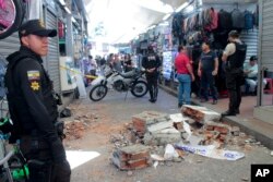 Policías vigilan una calle con escombros caídos de un edificio en un área comercial después de un fuerte terremoto, en Machala, Ecuador. (Foto AP/Stalin Díaz)