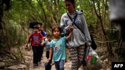 Una mujer camina con sus hijos a través del río Táchira, por las trochas que conectan a Venezuela con Colombia. 