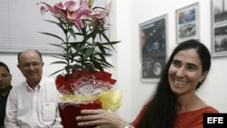 Yoani Sánchez (d), autora del blog "Generación Y", sonríe con un regalo recibido durante su primera jornada de visita a Brasil en Feira de Santana.