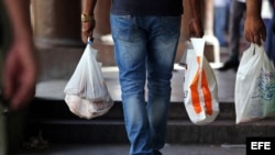  Varias personas caminan llevando bolsas plásticas, conocidas en Cuba como "jabitas".