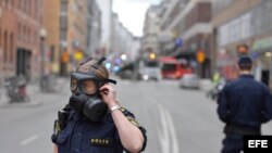 Miembros de la policía sueca se ajustan las máscaras antigas en la zona donde un camión que ha atropellado a varias personas y se ha estrellado contra una tienda de la calle comercial de Drottninggatan en el centro de Estocolmo, Suecia hoy 7 de abril de 2