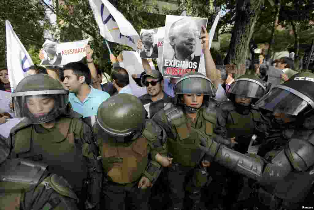 Miembros de la UDI sostienen en alto fotografías de senador Jaime Guzmán mientras demandan justicia frente a la embajada de Cuba en Chile. 