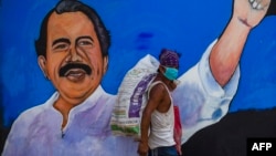 Un indigente pasa frente a un cartel del presidente de Nicaragua, Daniel Ortega, en Managua, el 9 de abril del 2020.