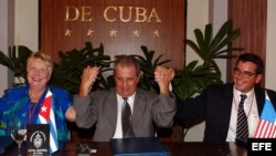Pedro Alvarez, entonces director de la empresa cubana Alimport, alza las manos de los senadores por el estado de Iowa Nancy Boettger (i) y Matt McCoy (d), tras la firma de un convenio.