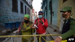 Un policía controla el acceso a una cuadra con casos de coronavirus, en La Habana. (Yamil LAGE / AFP)