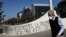 Un hombre que usa una mascarilla pasa junto a un graffiti contra el presidente chileno Sebastián Piñera en medio de la pandemia del coronavirus, en Santiago de Chile. (AP/Esteban Félix)