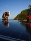 Denis Tamayo, de 30 años, y Alejandro Guerra, de 30, instalan un panel solar en la azotea de un edificio residencial en La Habana, Cuba, 16 de febrero de 2026. REUTERS/Norlys Perez