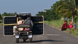 Cubanos transportan un panel solar en un triciclo por una carretera en la provincia de Pinar del Río, el 26 de julio de 2026. (Foto de YAMIL LAGE / AFP)