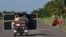 Cubanos transportan un panel solar en un triciclo por una carretera en la provincia de Pinar del Río, el 26 de julio de 2026. (Foto de YAMIL LAGE / AFP)