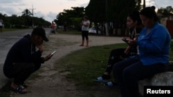 Cubanos chequean sus teléfonos durante un apagón en Matanzas.